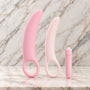 Dilatorset met vibraties op marmer: twee roze siliconen dilators met vingerlus en de bulletvibrator