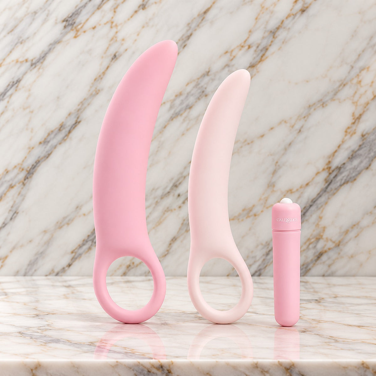 Dilatorset met vibraties op marmer: twee roze siliconen dilators met vingerlus en de bulletvibrator