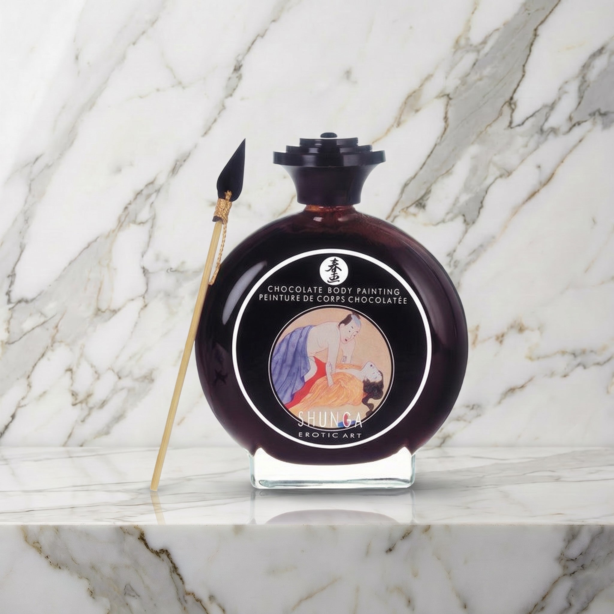 Ronde glazen fles chocolade bodypaint met penseeltje op een marmeren plank, Shunga