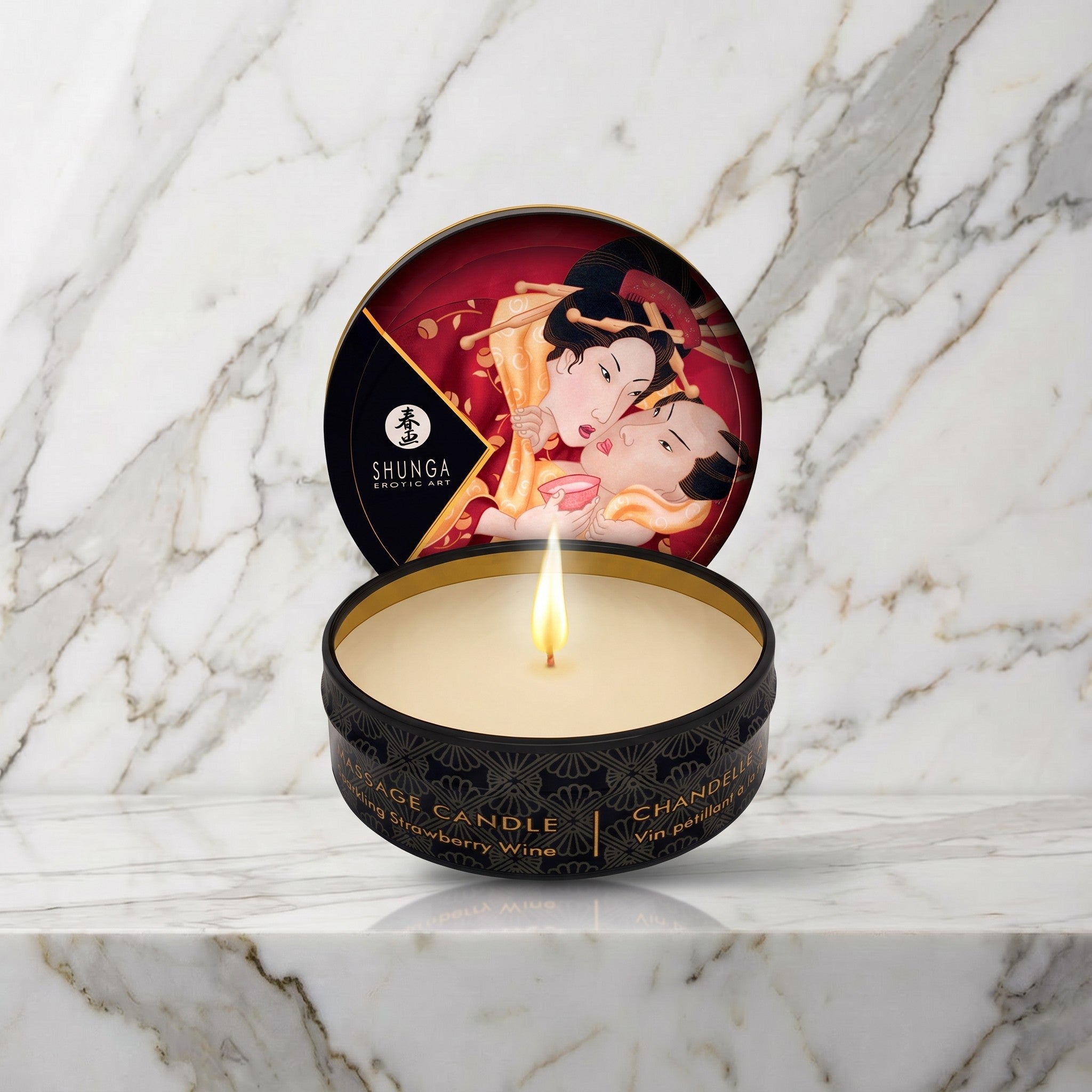 Shunga mini massagekaars Sparkling Strawberry Wine, open blikje met brandende kaars op een marmeren plank