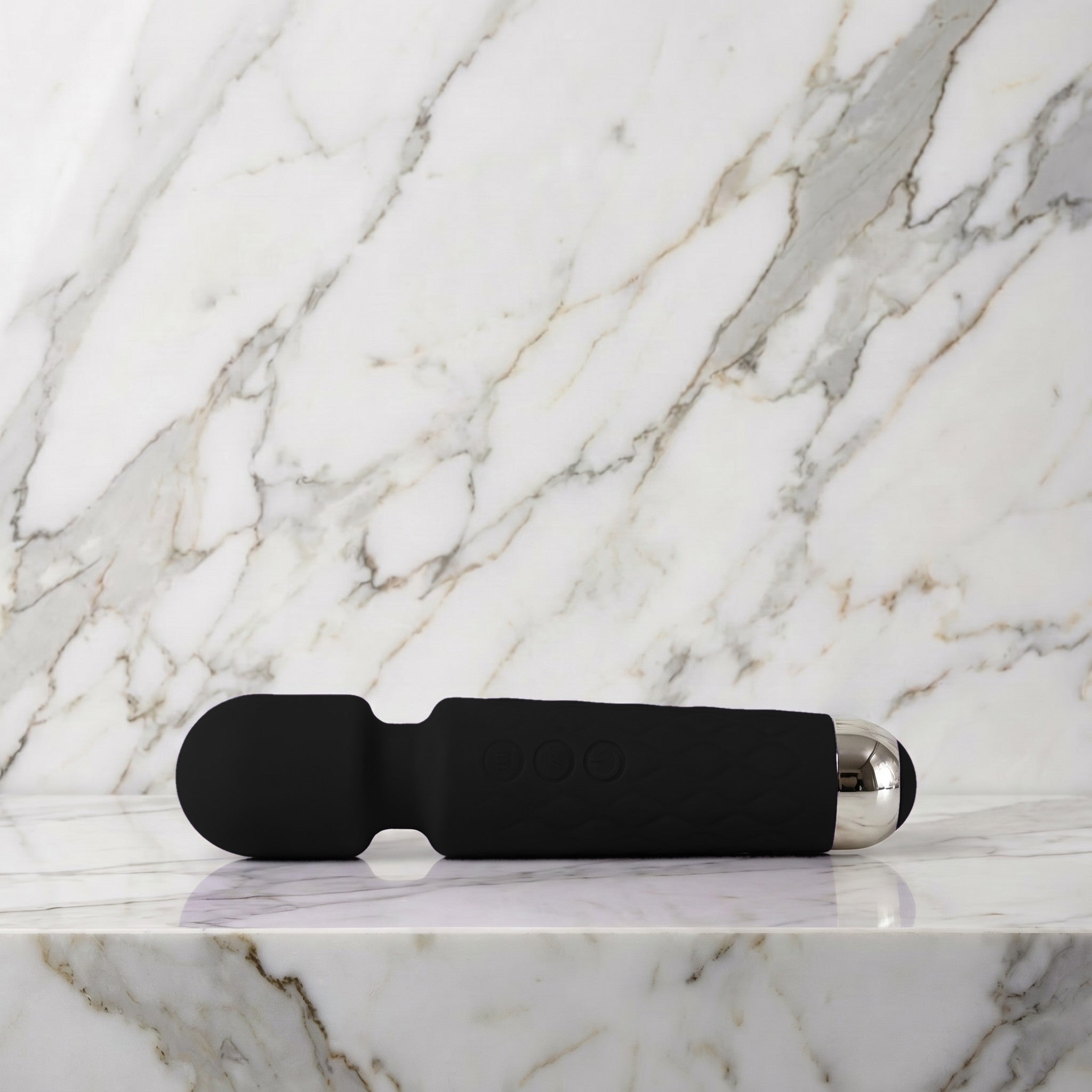 Zwarte Super Wand wandmassager klein formaat liggend op een lichte marmeren plank