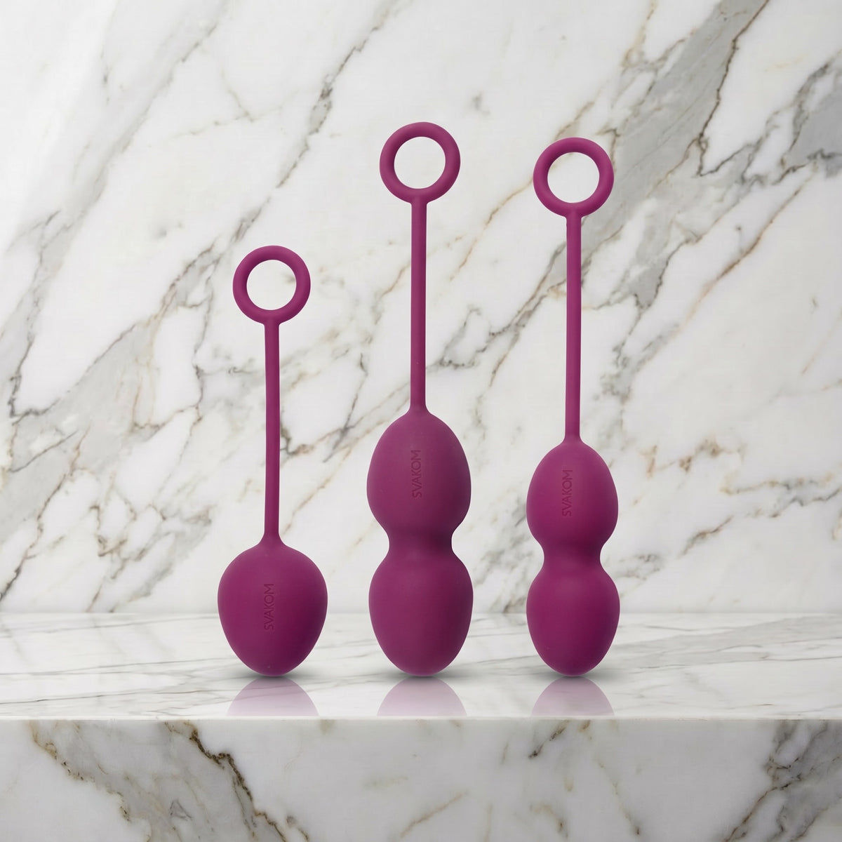 Drie paarse kegelballen met ringvormig koordje rechtop op een marmeren plank, Svakom Nova