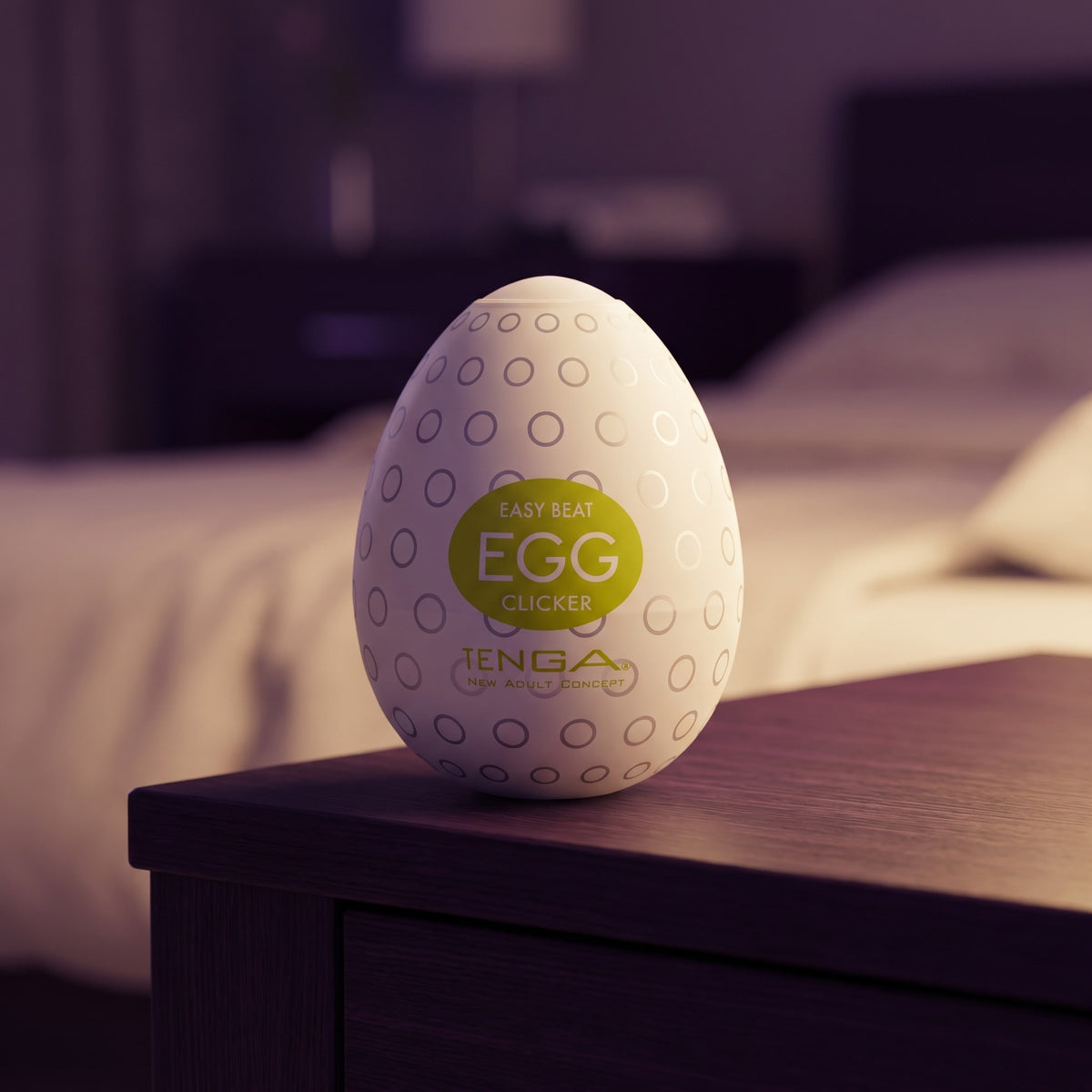 Sfeerbeeld: Tenga Egg Clicker rechtop op een donker houten nachtkastje in een slaapkamer