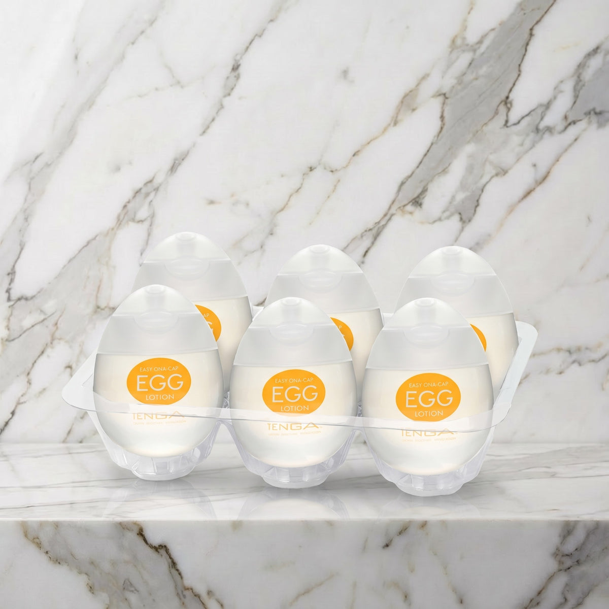 Zes eivormige flesjes glijmiddel in een tray op een marmeren plank, Tenga Egg Lotion