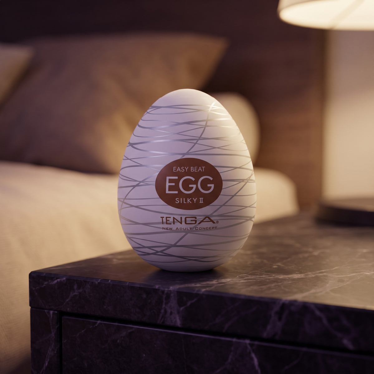 Sfeerbeeld: Tenga Egg Silky II op een donker marmeren nachtkastje bij een lamp