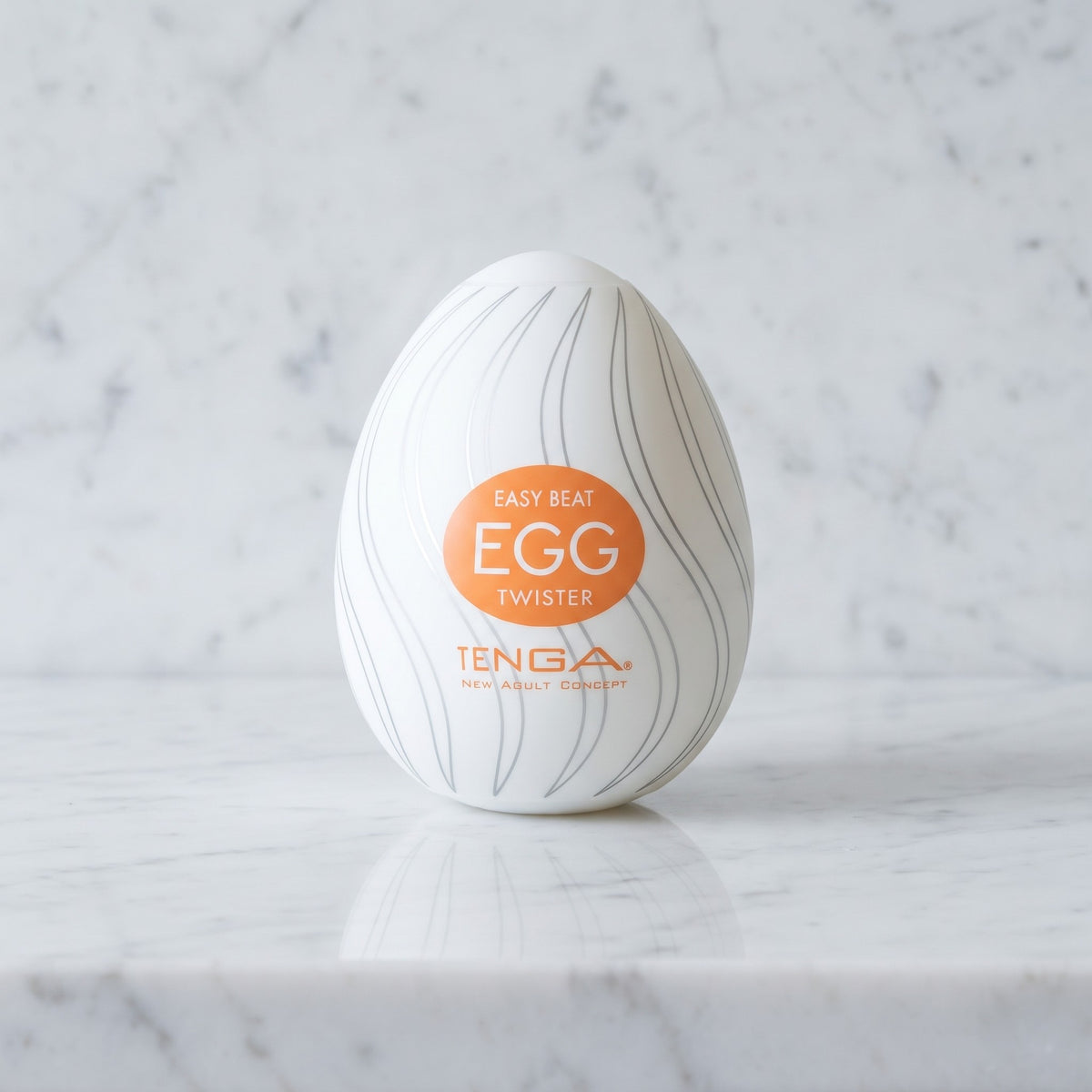 Wit masturbatie-ei met grijze spiraallijnen en oranje label op een marmeren plank, Tenga Egg Twister