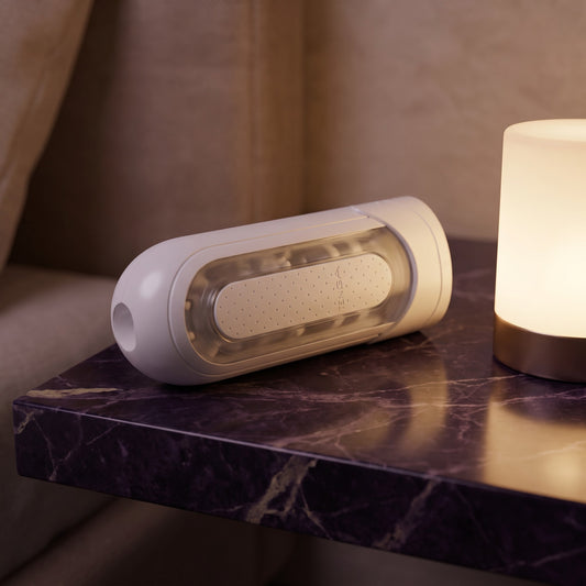 Sfeerbeeld: witte Flip Zero Electronic Vibrations liggend op een marmeren nachtkastje bij een lamp, Tenga
