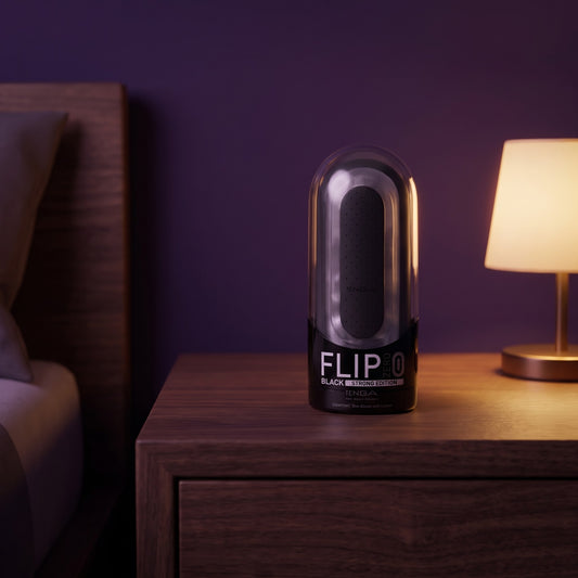 Sfeerbeeld: zwarte Tenga Flip Zero op een houten nachtkastje bij een lamp