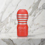 Rode Tenga Original Vacuum Cup rechtop op een marmeren plank