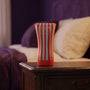 Sfeerbeeld: Tenga Soft Tube Cup rechtop op een houten nachtkastje in een slaapkamer