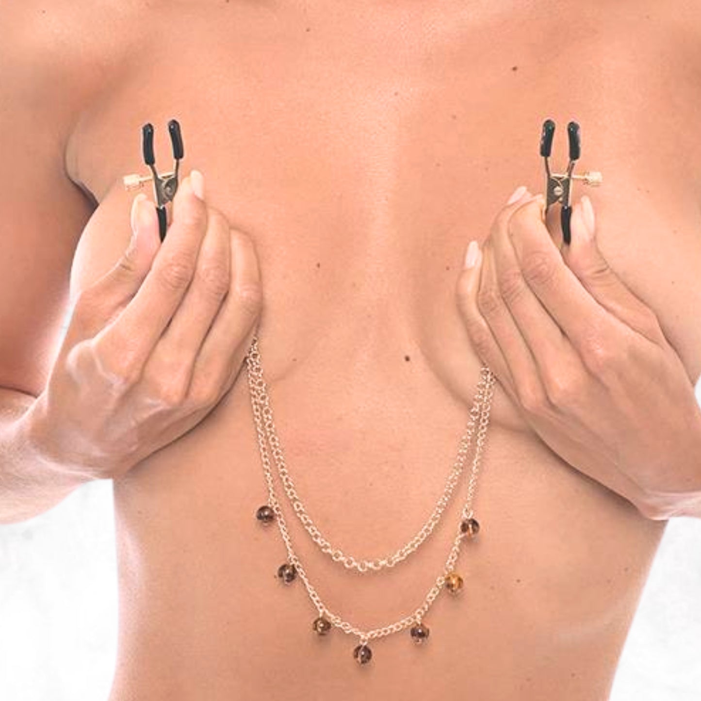 Tepelklemmetjes gedragen, goudkleurige ketting met amber steentjes elegant gedrapeerd