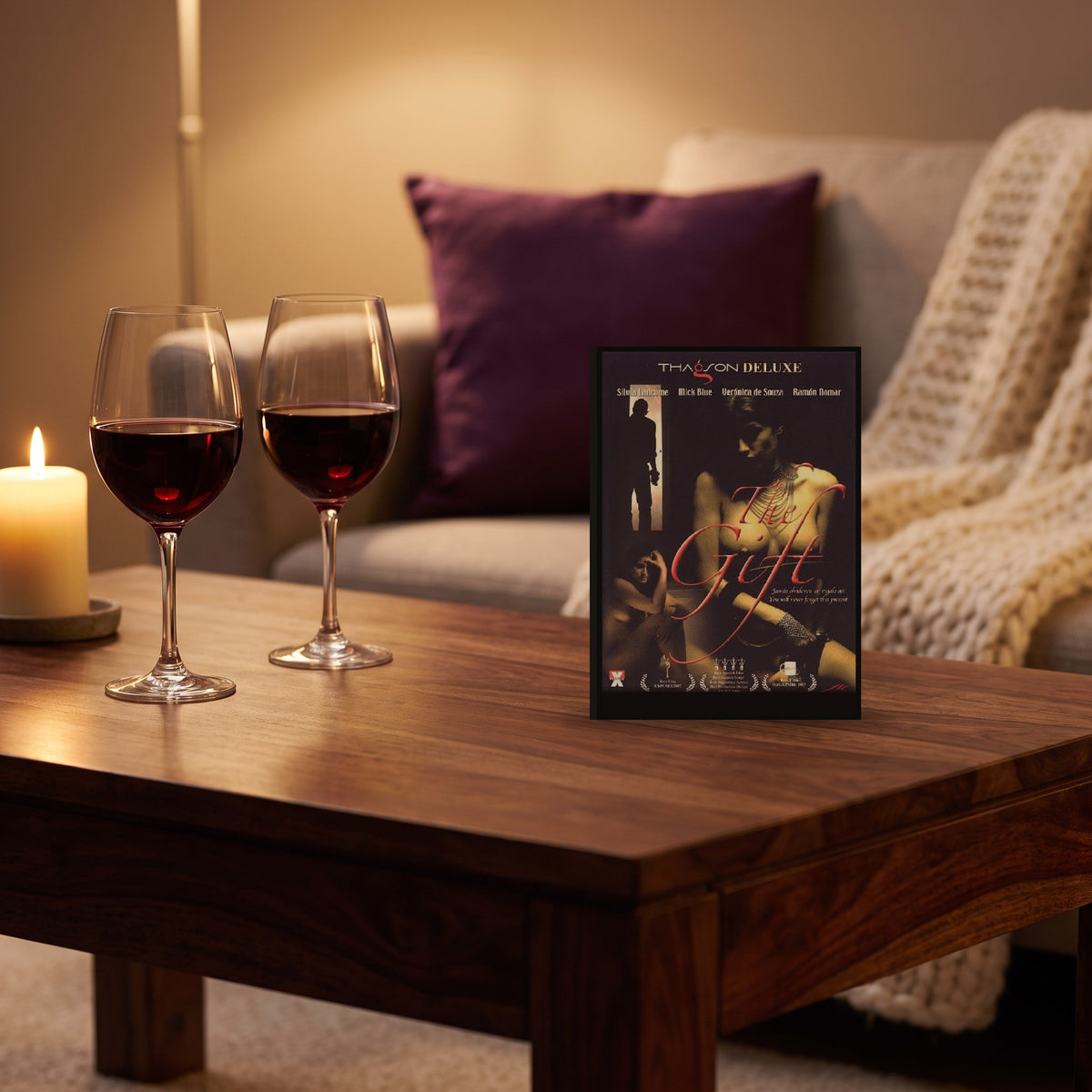 Sfeerbeeld: dvd The Gift op een salontafel naast twee glazen rode wijn en een kaars