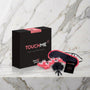 Zwarte doos met oogmasker, veertje en massageroller op een marmeren plank, Touch Me van Tease & Please
