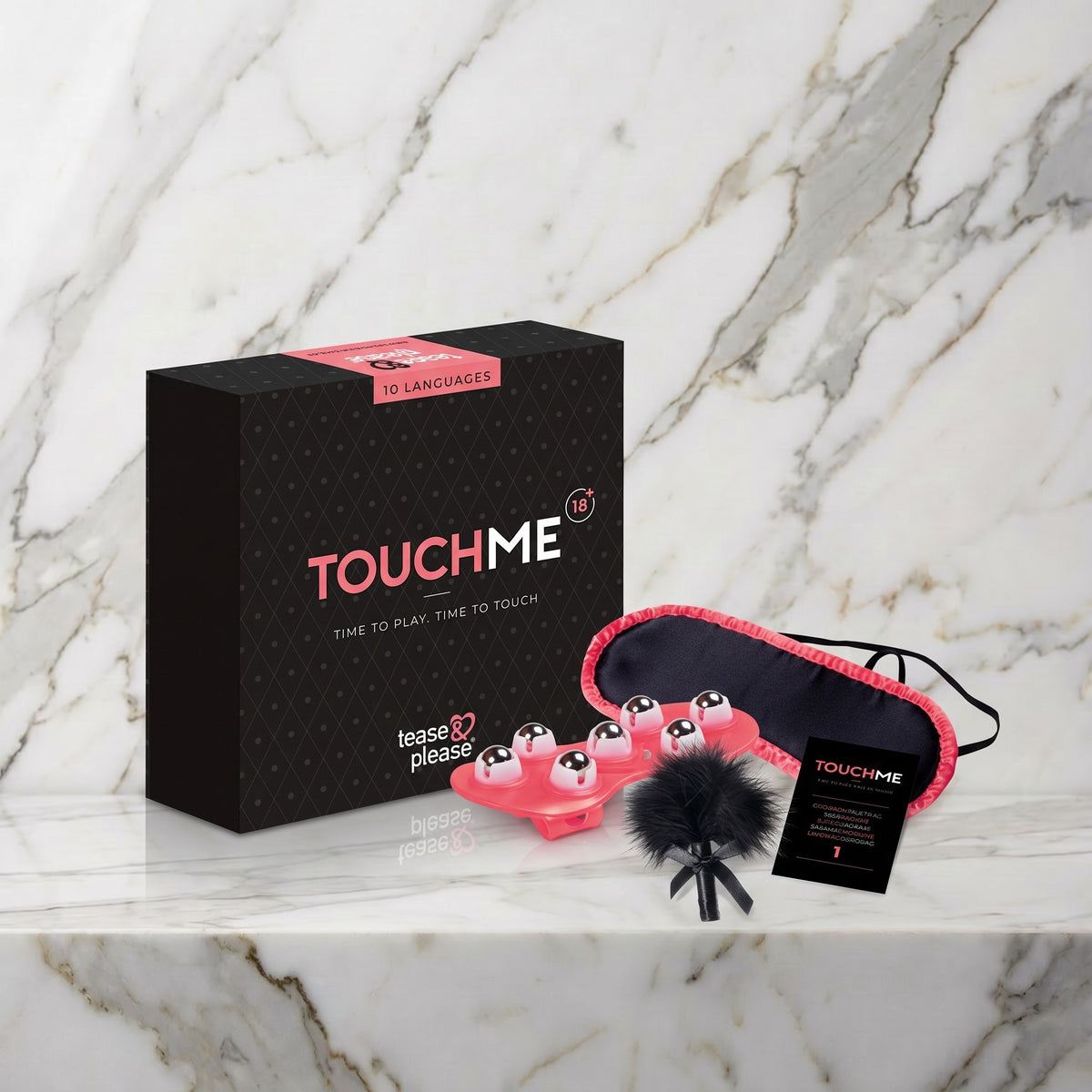 Zwarte doos met oogmasker, veertje en massageroller op een marmeren plank, Touch Me van Tease & Please