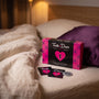 Sfeerbeeld: het spel Truth or Dare Erotic Couple(s) Edition op creme linnen naast een paars kussen