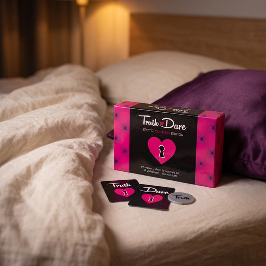 Sfeerbeeld: het spel Truth or Dare Erotic Couple(s) Edition op creme linnen naast een paars kussen