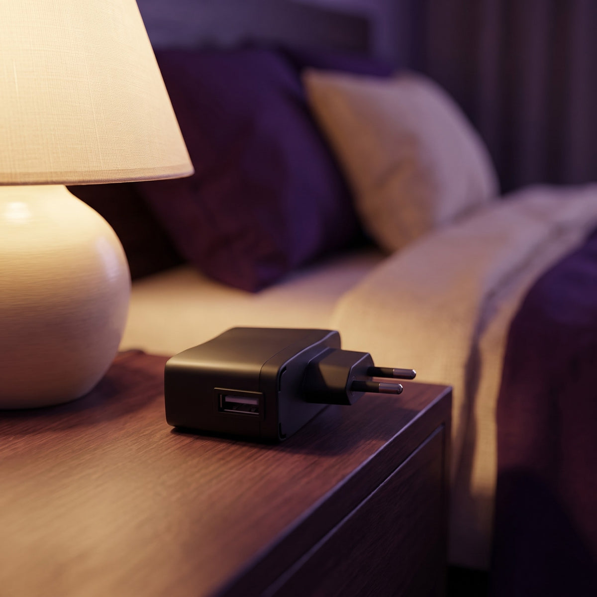Sfeerbeeld: zwart USB-oplaadblok op een nachtkastje naast een brandende lamp