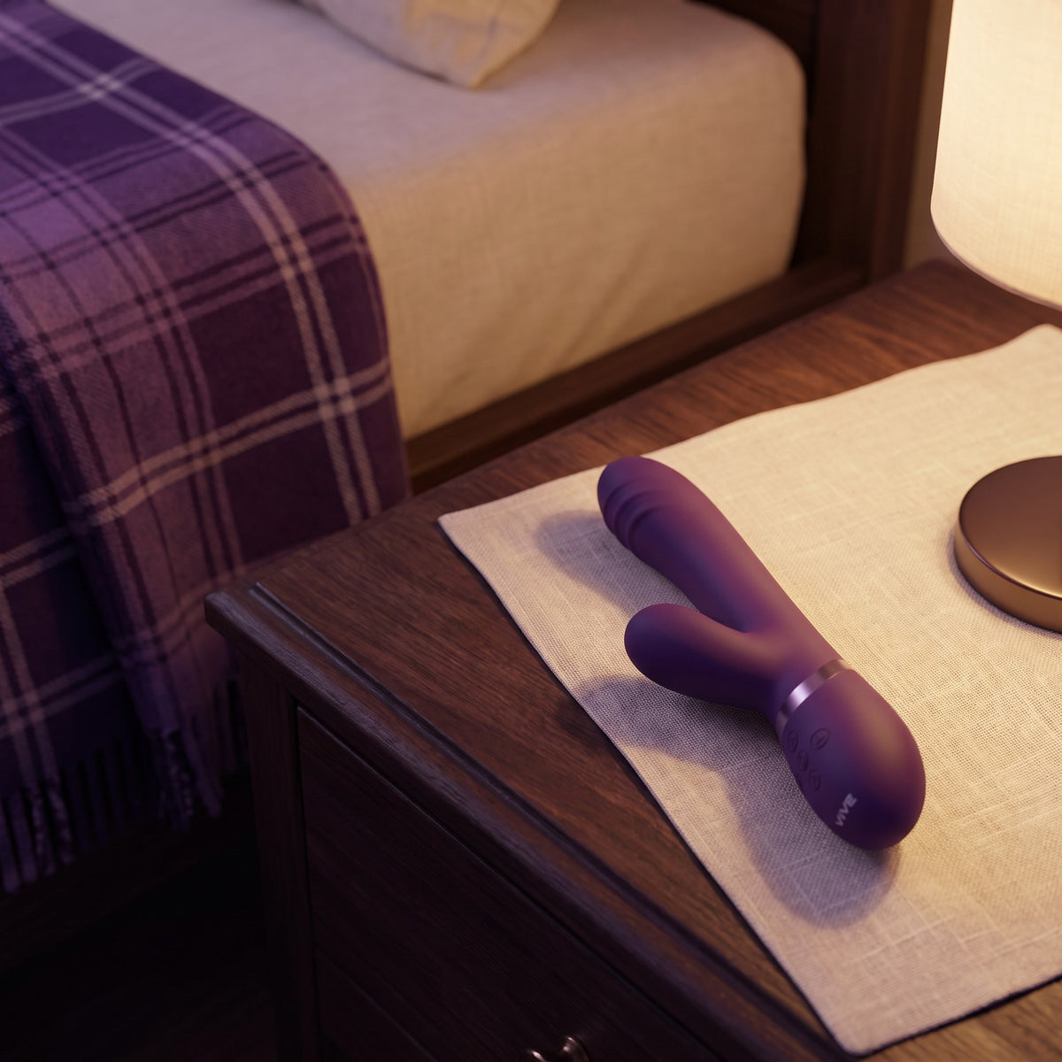 Sfeerbeeld: de paarse Vive Tani rabbit vibrator op een nachtkastje bij lamplicht, van Vive