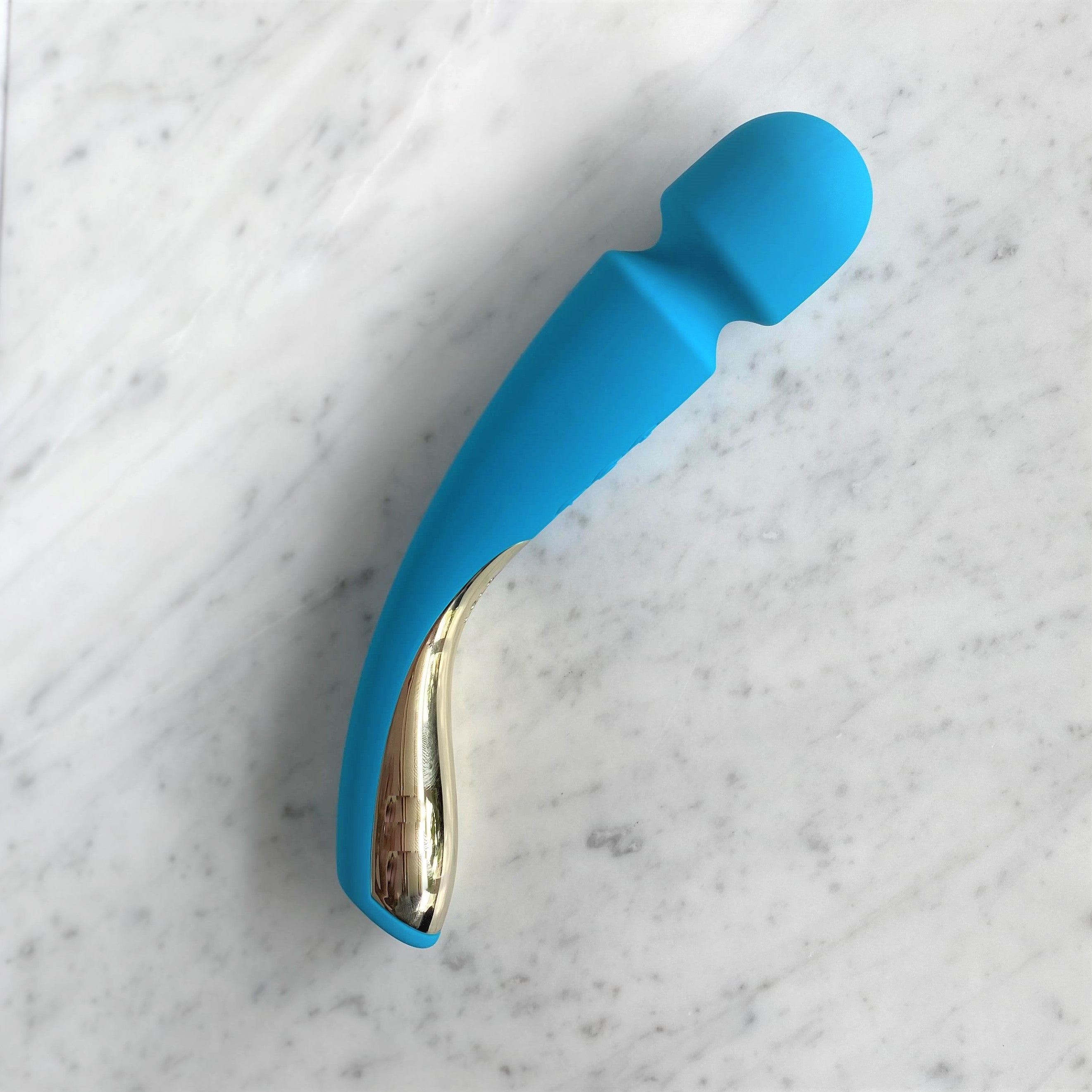 Blauwe LELO Smart Wand 2 Medium op marmer, met de knoppen en de gouden handgreep