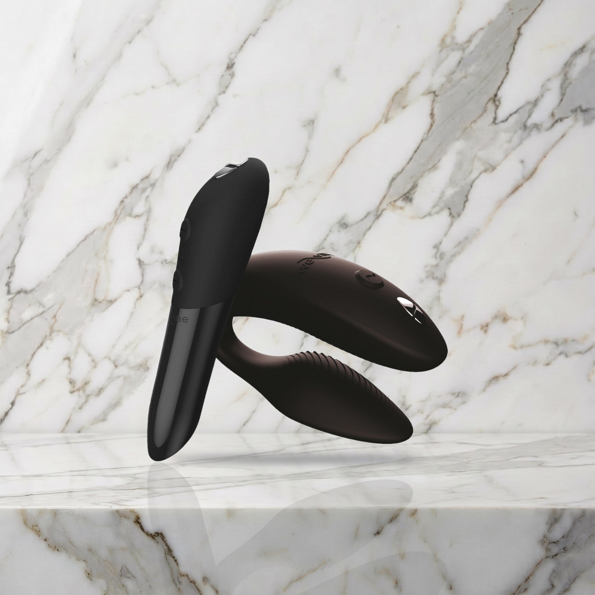 Zwarte Sync 2 koppelvibrator en Tango X mini vibrator op een marmeren plank, We-Vibe