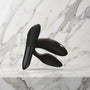 Zwarte Sync 2 koppelvibrator en Tango X mini vibrator op een marmeren plank, We-Vibe