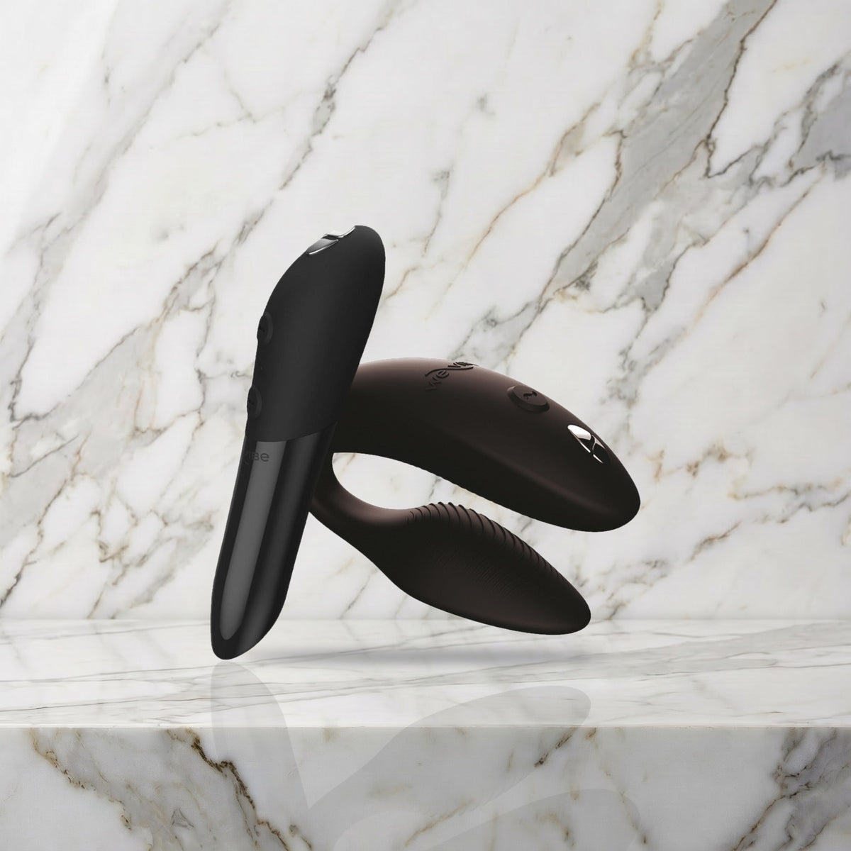 Zwarte Sync 2 koppelvibrator en Tango X mini vibrator op een marmeren plank, We-Vibe