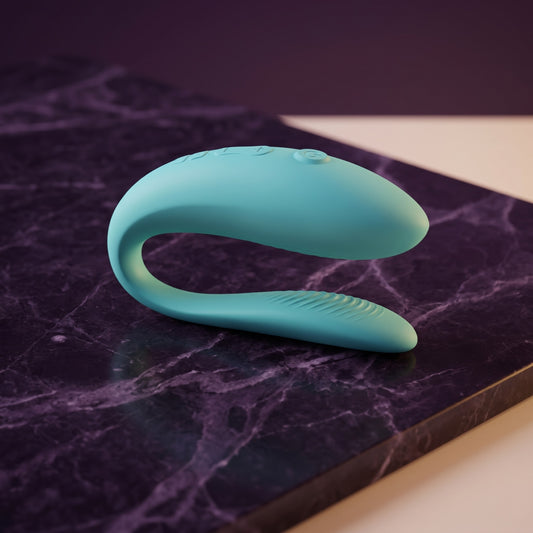 Sfeerbeeld: We-Vibe Sync Lite in aqua op donkerpaars marmer in gedempt licht