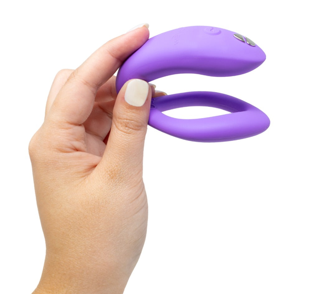 We-Vibe Sync O in hand, toont compact U-vormig ontwerp met bedieningsknoppen