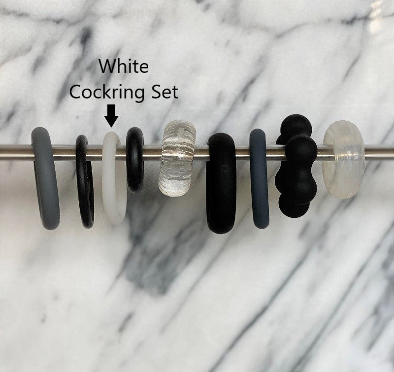Witte cockring tussen andere cockringen aan een stang, ter vergelijking van de dikte, White Cockring Set