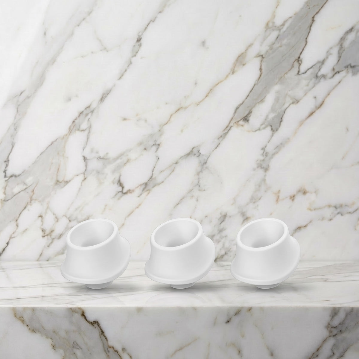 Drie witte siliconen mondkapjes met schuine rand op een marmeren plank, Womanizer