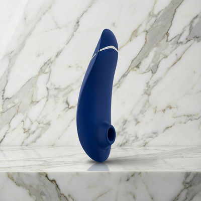 Womanizer Premium 2 luchtdrukstimulator in blauw, rechtop op een marmeren plank