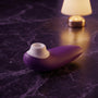 Sfeerbeeld: paarse Womanizer Starlet 3 liggend op donkerpaars marmer in gedempt licht